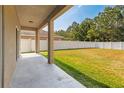 A spacious, green backyard featuring a large lawn, white fence, and covered patio area at 13174 Royal Pines Ave, Riverview, FL 33579