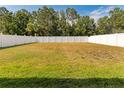 Spacious backyard showcasing a large green lawn enclosed by a white fence at 13174 Royal Pines Ave, Riverview, FL 33579