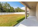 A spacious backyard featuring a large lawn, white fence, and covered patio at 13174 Royal Pines Ave, Riverview, FL 33579