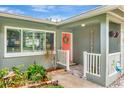 Cozy front porch with green brick, a red door and white railings, surrounded by lush landscaping at 1398 Lemon St, Clearwater, FL 33756