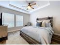 Serene bedroom showcasing a decorative headboard, soft gray linens, and tray ceiling at 18001 Richmond Place Dr # 330, Tampa, FL 33647