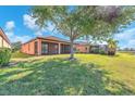 Spacious backyard with lush lawn, mature tree, and screened-in lanai at 310 Cedar Falls Dr, Apollo Beach, FL 33572