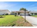 Single-story home with a well-manicured lawn, mature landscaping, and an attached two-car garage at 3956 Tarpon Pointe Cir, Palm Harbor, FL 34684