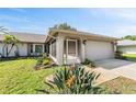 Inviting single-story home featuring a lush front yard with tropical plants and a screened entryway at 3956 Tarpon Pointe Cir, Palm Harbor, FL 34684