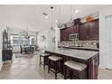 Elegant kitchen featuring dark wood cabinets, granite countertops, an island with seating, and stainless steel appliances at 4195 Barletta Ct, Wesley Chapel, FL 33543