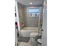 Bright bathroom featuring a tub with gray tiling and a light floral shower curtain and a toilet at 7525 Arbordale Dr, Port Richey, FL 34668
