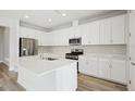 Modern kitchen featuring white cabinets, stainless steel appliances, a center island, and sleek countertops at 8514 Dove Bog Ter, Parrish, FL 34219