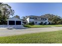 Two-story home with a balcony, dark shutters, two-car garage and driveway situated on a well-kept lawn at 1089 Virginia St, Dunedin, FL 34698