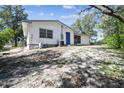 Exterior view showcasing the backyard, the white siding, and a blue door on a sunny day at 11409 Spring Hill Dr, Spring Hill, FL 34609