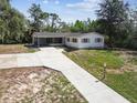 Aerial view of a well-maintained home showcasing the front yard, driveway, and lush surrounding landscape at 11409 Spring Hill Dr, Spring Hill, FL 34609