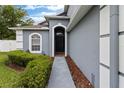 Inviting front entrance featuring an arched doorway, lush bushes, and exterior lighting at 1948 Grenville Ct, Wesley Chapel, FL 33543