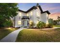 Charming two-story home at twilight with black and white accents and verdant lawn at 2306 Trelain S Dr, St Petersburg, FL 33712
