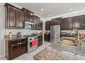 Modern kitchen featuring stainless steel appliances, granite countertops, dark wood cabinetry, and a subway tile backsplash at 3212 Calvano Dr, Land O Lakes, FL 34639