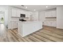 Bright kitchen featuring white cabinets, stainless steel appliances, an island and wood-look flooring at 4210 Goldfoil Rd, Spring Hill, FL 34609