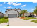 This gray, two-story home features a two-car garage, lush landscaping, and a well-maintained lawn at 10623 Bahama Woodstar Ct, Riverview, FL 33579
