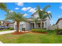 Charming two-story home features a well-manicured lawn, gray exterior, complemented by mature palm trees and a two-car garage at 10623 Bahama Woodstar Ct, Riverview, FL 33579