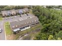 Back aerial view of townhome community with ample parking and lush green landscaping at 1250 Charlesworth Dr, Wesley Chapel, FL 33543