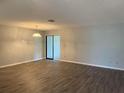 Spacious living room featuring wood-look vinyl flooring, modern paint, and sliding glass doors at 13742 14Th St, Dade City, FL 33525
