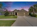 Inviting single-story home with a well-manicured lawn, a two-car garage, and neutral-toned exterior paint at dusk at 17516 Bright Wheat Dr, Lithia, FL 33547