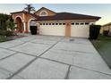 Charming home featuring an arched entryway and a spacious three-car garage with a concrete driveway at 18104 Sweet Jasmine Dr, Tampa, FL 33647