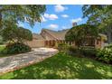 Well-maintained single-story home featuring an attached garage and beautiful landscaping in a tree-filled yard at 1951 Downing Pl, Palm Harbor, FL 34683