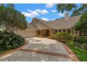 Exterior view of the house featuring a two-car garage, manicured yard, and brick-lined driveway at 1951 Downing Pl, Palm Harbor, FL 34683
