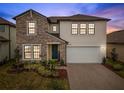 Charming two-story home featuring stone accents, a two-car garage, and a beautifully landscaped front yard at 22294 Storybook Cabin Way, Land O Lakes, FL 34637