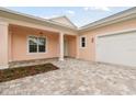 Exterior view of a peach house with white trim, two-car garage, and palm trees at 2973 Breezy Meadows, Clearwater, FL 33760