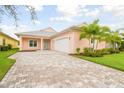 Charming peach-colored home with a paver driveway and well-manicured landscaping at 2973 Breezy Meadows, Clearwater, FL 33760