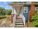 Exterior shot displaying the steps leading to the charming covered front porch with brick and white railing at 4016 N Seminole Ave, Tampa, FL 33603