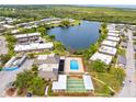 An aerial view of a residential area highlighting a community pool, shuffleboard, and nearby lake at 4305 Summersun Dr, New Port Richey, FL 34652