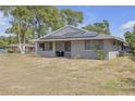 Inviting single-story home with a gray exterior, solar panels and a partially shaded front yard at 4623 Wisteria Dr, Zephyrhills, FL 33542