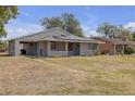 Charming gray home featuring a front yard with partial shade, and a convenient carport at 4623 Wisteria Dr, Zephyrhills, FL 33542