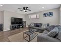 Cozy living room features a modern ceiling fan, comfortable gray sofas, and contemporary decor at 4623 Wisteria Dr, Zephyrhills, FL 33542