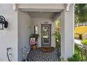 Charming covered front porch with gray tiled floor, house number, lantern, potted plants, and a decorative front door at 6140 Marina Cove S Way, St Petersburg, FL 33712