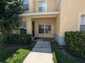 Townhome exterior featuring covered entry, manicured bushes, and well-maintained lawn at 6250 Maisie Rd, Zephyrhills, FL 33542