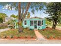 Charming turquoise home with a cozy front porch, mature landscaping, and a lush green lawn at 653 E Spruce St, Tarpon Springs, FL 34689