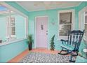 Inviting turquoise front porch featuring a rocking chair and stylish decor at 653 E Spruce St, Tarpon Springs, FL 34689