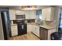 Well-lit kitchen with white cabinets, stainless steel appliances, and granite countertops at 9926 Gray Fox Ln, Port Richey, FL 34668