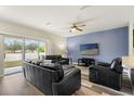 Cozy living room boasts modern flooring, a ceiling fan, and a sliding glass door to the backyard at 9960 Hound Chase Dr, Gibsonton, FL 33534