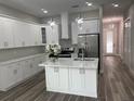Modern kitchen with white cabinets, stainless steel appliances, center island, and view to the living area at 12308 Pittsfield Ave, Tampa, FL 33624