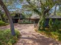 Elegant home featuring a brick driveway and mature trees enhancing curb appeal at 1296 Weybridge Ln, Dunedin, FL 34698
