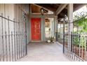 Inviting front porch with a bright red door framed by wrought iron and views of verdant foliage at 1296 Weybridge Ln, Dunedin, FL 34698