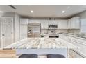 A kitchen island with barstool seating in a modern kitchen with white cabinets and stainless steel appliances at 13822 Harvestwood Ln, Riverview, FL 33569