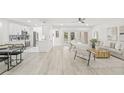 Open-concept living room featuring light wood floors, a ceiling fan, and a modern kitchen in the background at 13934 Clubhouse Cir # 8, Tampa, FL 33618