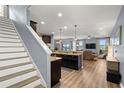 A kitchen flows seamlessly into living room with granite counters, dark cabinets, stainless appliances and pendant lighting at 1726 Hadden Hall Pl, Trinity, FL 34655
