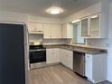 Modern kitchen with stainless steel appliances, granite countertops, white cabinets, and new floors at 2075 Plateau Rd, Clearwater, FL 33755