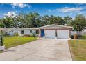 Lovely single-story home with a brick-accented facade, blue door, two-car garage, and beautiful landscaping at 308 Jeanal Pl, Tampa, FL 33612