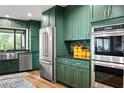 Modern kitchen with stainless steel appliances, green cabinets, and wood floors at 4009 Carrollwood Village Dr, Tampa, FL 33618