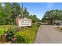 Woodside Village Condominiums sign with lush greenery, set in a quiet neighborhood with mature trees at 4215 East Bay Dr # 1103D, Clearwater, FL 33764